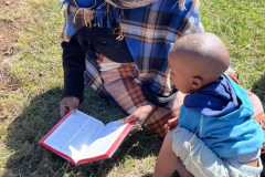 One of the villagers sharing her Bible with one of the kids.